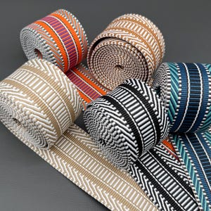 Puede incluir: Varios rollos de cintas tejidas de colores con diferentes diseños. Las cintas presentan diseños en naranja, morado, negro, blanco, beige y azul. Adecuadas para manualidades y decoración.