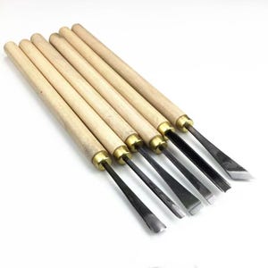 Puede incluir: Juego de seis herramientas para tallar madera. Cada herramienta tiene un mango de madera y una hoja de metal. Las hojas tienen diferentes formas para trabajos de carpintería detallados. Los mangos son de madera clara con virolas doradas.