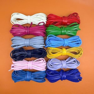 May include: Twelve bundles of flat leather cord arranged in a grid, featuring a variety of colors including white, red, magenta, green, light gray, light blue, dark navy, yellow, light pink, lavender, medium blue, and royal blue.