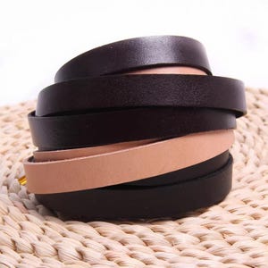 Peut inclure: Une pile de lanières de cuir de différentes nuances de marron et de noir. Les lanières sont disposées en spirale, mettant en valeur les différentes couleurs et textures du cuir. Les lanières sont sur une surface tissée.
