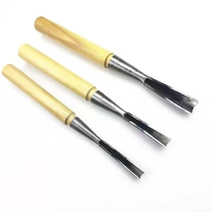 May include: Three wood carving chisels. Each has a light-coloured wooden handle and a metal blade. The blades are curved. The tools are arranged diagonally against a white background. These chisels are designed for detailed woodworking.
