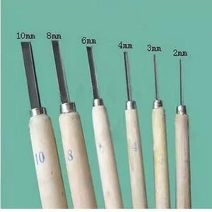Puede incluir: Un juego de seis herramientas para tallar madera con diferentes anchos de cuchilla, de 2 mm a 10 mm. Las cuchillas son plateadas y los mangos son de madera clara. Fondo turquesa.