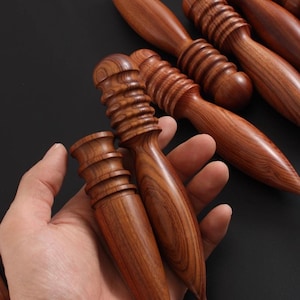 Könnte beinhalten: Eine Sammlung von Lederhandwerkzeugen aus Holz, darunter Polierer und Kantenformer. Die Werkzeuge bestehen aus einem satten, rotbraunen Holz mit sichtbaren Maserungsmustern. Die Werkzeuge haben verschiedene Formen und Größen.