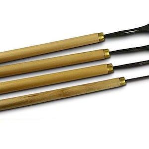 Peut inclure: Quatre outils de sculpture sur bois avec des manches en bois et des lames en métal. Les lames ont des formes différentes, dont une gouge incurvée et un ciseau droit. Les outils sont disposés en diagonale sur fond blanc.