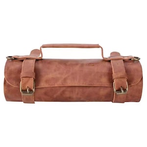May include: A cylindrical, brown leather bag with a handle and two adjustable straps secured with brass buckles. The bag has a distressed finish, suggesting a vintage or rustic style. The bag is designed to be carried by hand.