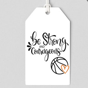Puede incluir: Etiqueta blanca con texto negro que dice "Sé fuerte y valiente" con un balón de baloncesto negro y un corazón naranja.