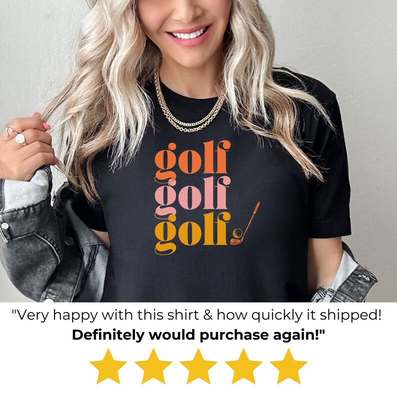 May include: Black t-shirt with the word "golf" repeated three times in stacked, colorful text. The word "golf" is in orange, pink, and yellow. A golf club and ball are to the right of the text.