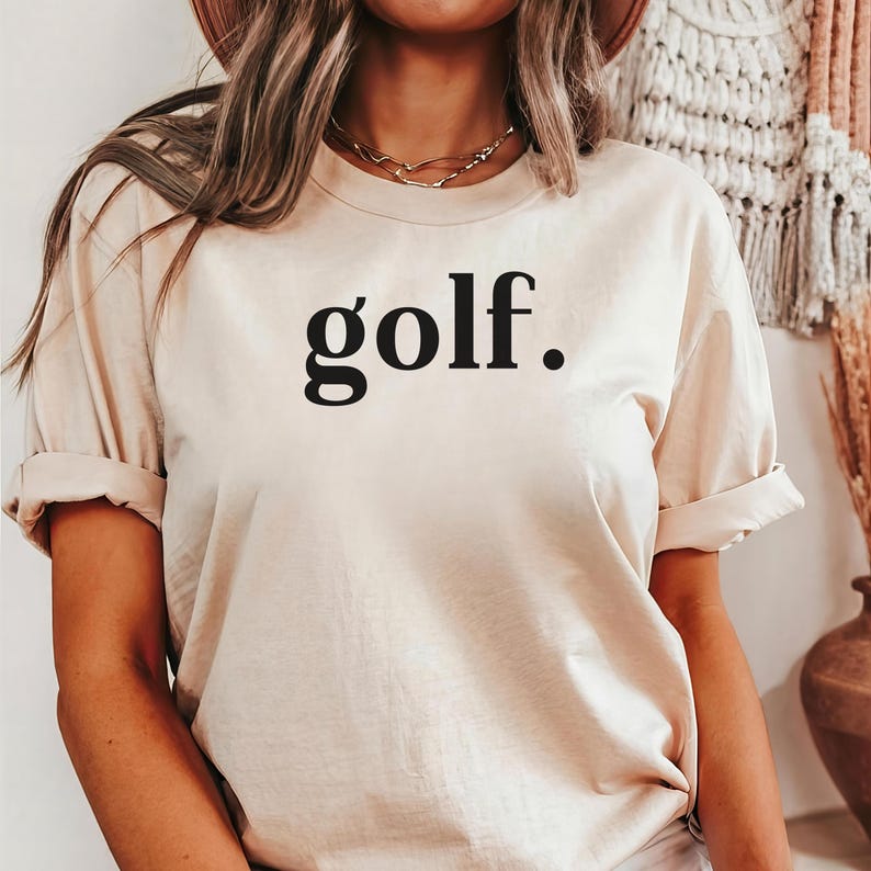 Woman wearing a beige “golf.” t-shirt tucked into jeans — simple and stylish golf shirt for everyday wear.