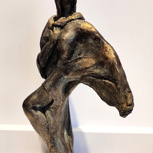 May include: A bronze sculpture of a woman in a flowing robe. The sculpture is abstract and has a textured surface.