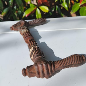 Può includere: Una maniglia per porta in metallo arrugginito con un design unico che presenta due mani intrecciate. La maniglia è in ghisa e ha un colore marrone scuro.