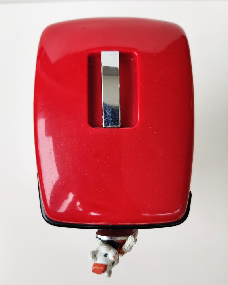 May include: A red plastic mouse trap with a silver metal trigger. The trap is designed to catch mice.