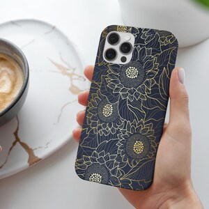 May include: A navy blue phone case with a gold sunflower pattern. The case has a cutout for the camera lens.