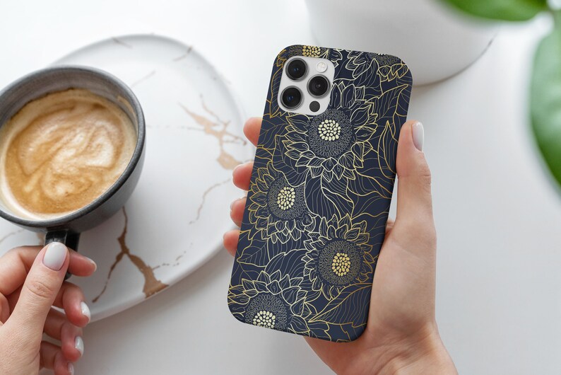 May include: A navy blue phone case with a gold sunflower pattern. The case has a cutout for the camera lens.
