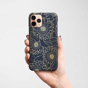 May include: A navy blue phone case with a gold sunflower pattern. The case has a cutout for the camera lens.