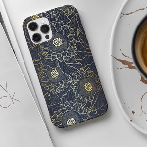 May include: A navy blue phone case with a gold floral design featuring sunflowers. The case has a cutout for the phone's camera.
