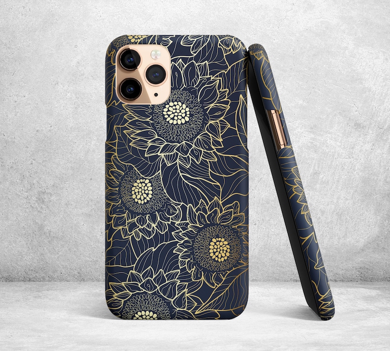 May include: A navy blue phone case with a gold floral design featuring sunflowers. The case has a cutout for the phone's camera.