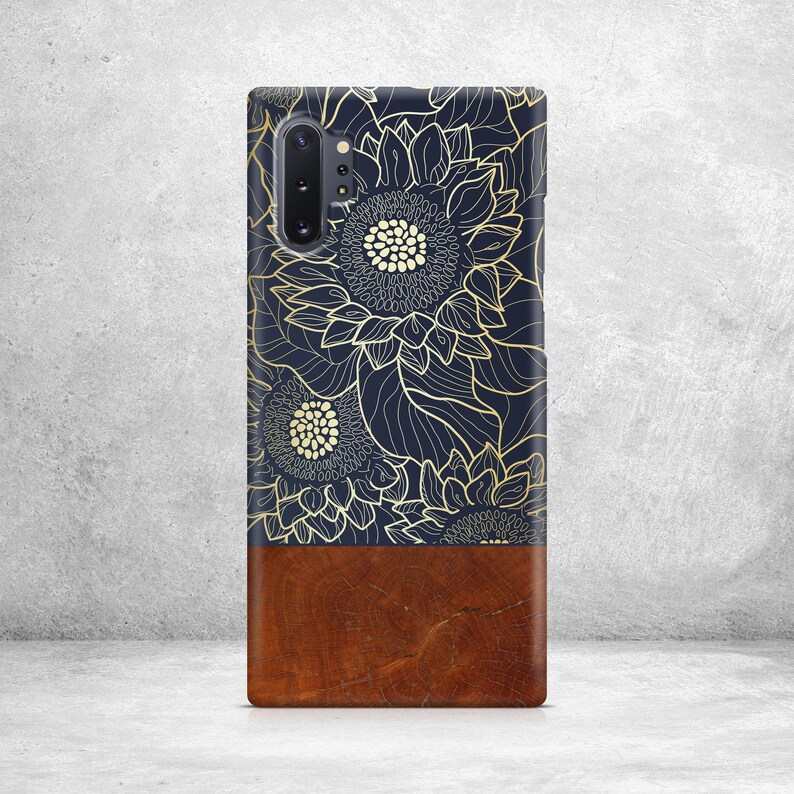May include: A phone case with a dark blue background and a gold floral design. The bottom half of the case is a brown wood grain pattern.
