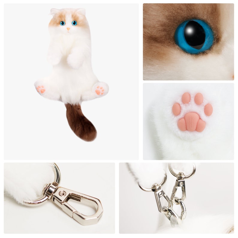 May include: White and brown plush cat keychain with blue eyes. The cat is sitting up with its paws in the air. The keychain has a silver metal clasp.