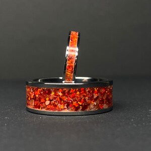 Op de afbeelding: Twee ringen van roestvrij staal met een band van oranje glitter ingebed in het metaal.