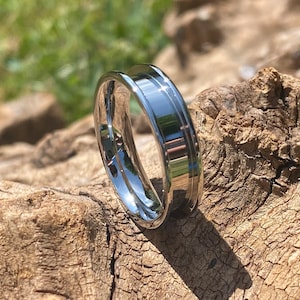 May include: A silver ring with a bevelled edge and a polished finish.