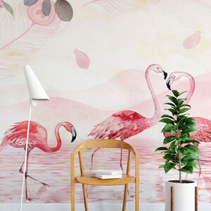 May include: A watercolour wall mural featuring pink flamingos standing in a pink and white water scene. The mural is decorated with pink feathers and rose petals. A wooden chair and a potted plant are in the foreground.