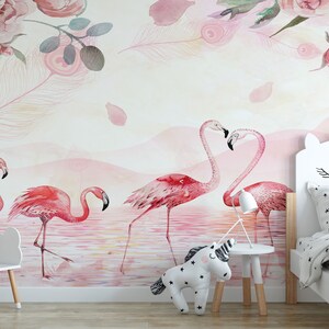 May include: A pink and white nursery with a unicorn headboard on a bed with a pink and white star patterned duvet. The wall has a pink watercolour mural with pink flamingos and pink flowers.