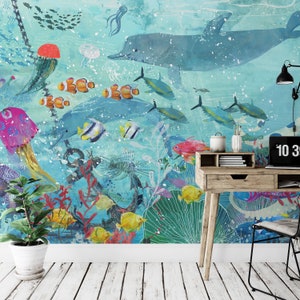May include: A colorful underwater scene with a large blue dolphin, a variety of fish, coral, and an anchor. The scene is painted on a wall with a desk and chair in front of it.