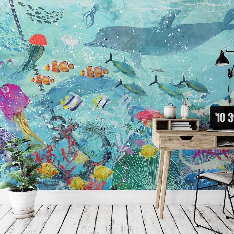 May include: A colorful underwater scene with a large blue dolphin, a variety of fish, coral, and an anchor. The scene is painted on a wall with a desk and chair in front of it.