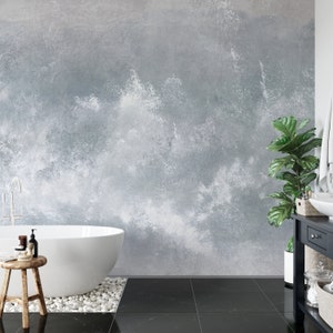 May include: A white bathtub sits in a bathroom with a gray concrete wall, black tile floor, and a potted plant.