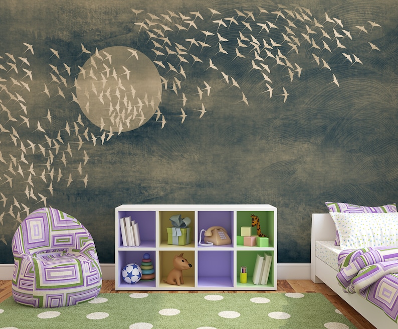 May include: A child's bedroom with a mural of a full moon and flying birds. The room features a patterned beanbag chair, a white cube shelf with toys and books, a bed with purple bedding, and a green polka-dot rug.