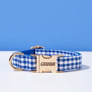 Puede incluir: Collar de perro de gingham azul y blanco con una hebilla dorada que dice "GRAHAM".