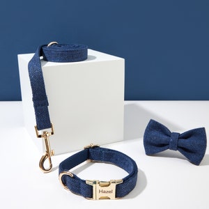 May include: A blue dog collar with a gold buckle and the name "Hazel" engraved on it. A matching blue leash and bow tie are also pictured.