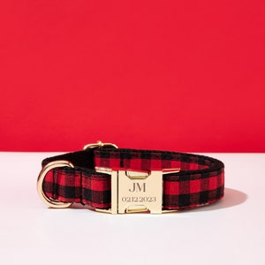 May include: Red and black plaid dog collar with a gold buckle. The buckle is engraved with the initials "JM" and the date "02122023".
