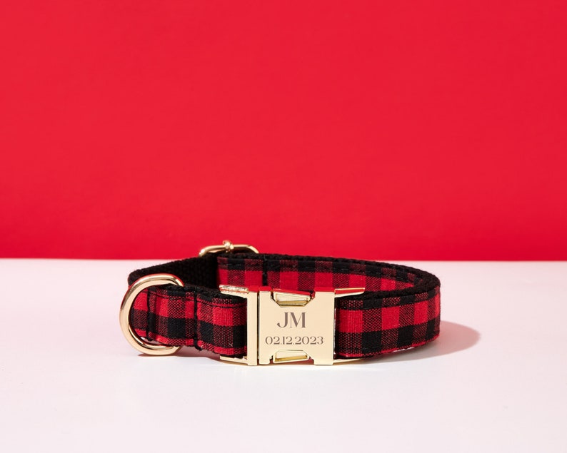 May include: Red and black plaid dog collar with a gold buckle. The buckle is engraved with the initials "JM" and the date "02122023".