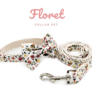 K&ouml;nnte beinhalten: Ein florales Halsband-Set f&uuml;r Haustiere, bestehend aus einem cremefarbenen Halsband, einer Fliege und einer Leine. Das Set ist mit einem Muster aus kleinen Blumen in Rot-, Gelb- und Gr&uuml;nt&ouml;nen verziert. Der Text "Floret COLLAR SET" wird in Rosa angezeigt.
