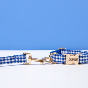 Puede incluir: Conjunto de collar y correa para perro de gingham azul y blanco con una hebilla dorada grabada con el nombre "GRAHAM".