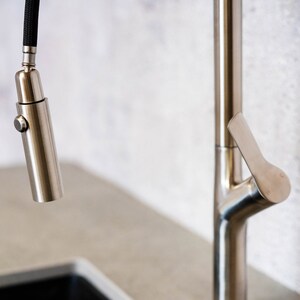 May include: A brushed nickel kitchen faucet with a pull-down sprayer and a lever handle.