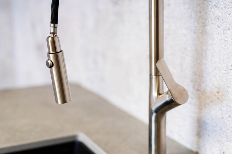 May include: A brushed nickel kitchen faucet with a pull-down sprayer and a lever handle.