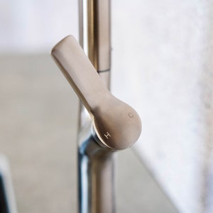 May include: Close-up of a silver faucet handle with the letters 'H' and 'C' engraved on the knob.