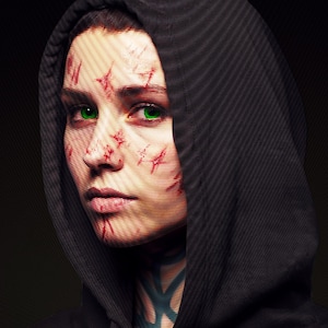 May include: A portrait of a person wearing a black hooded sweatshirt. The face features bright green eyes and several red, linear markings across the skin. The neck displays a dark, intricate, geometric pattern tattoo against a black background.