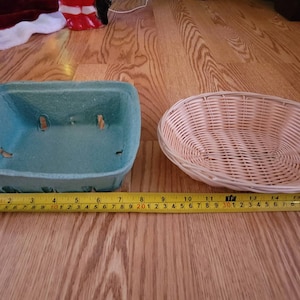 May include: Two empty baskets, one is a light blue cardboard basket and the other is a light brown wicker basket.