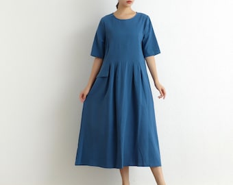 May include: A blue midi dress with a round neckline and short sleeves. The dress has a pocket on the left side and a pleated skirt.