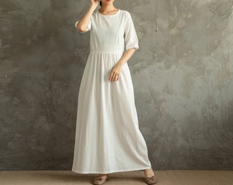 May include: A white maxi dress with a round neckline and short sleeves. The dress has a gathered waist and a flowing skirt.