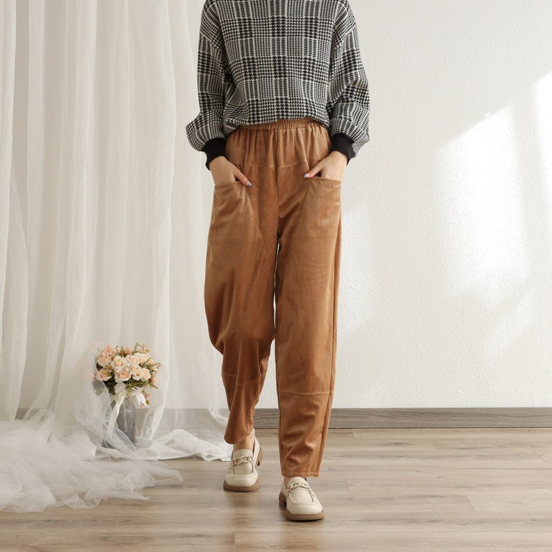 Puede incluir: Una persona con un su&eacute;ter a cuadros blanco y negro y pantalones de pana marrones con bolsillos. Los pantalones se combinan con mocasines color crema. El atuendo es informal y c&oacute;modo, adecuado para el uso diario.