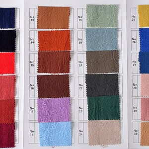 May include: A fabric swatch card with 36 different fabric samples. The samples are arranged in rows of four, with each row labeled with a number. The fabric samples are a variety of colors, including white, black, red, orange, brown, purple, blue, green, yellow, and pink.