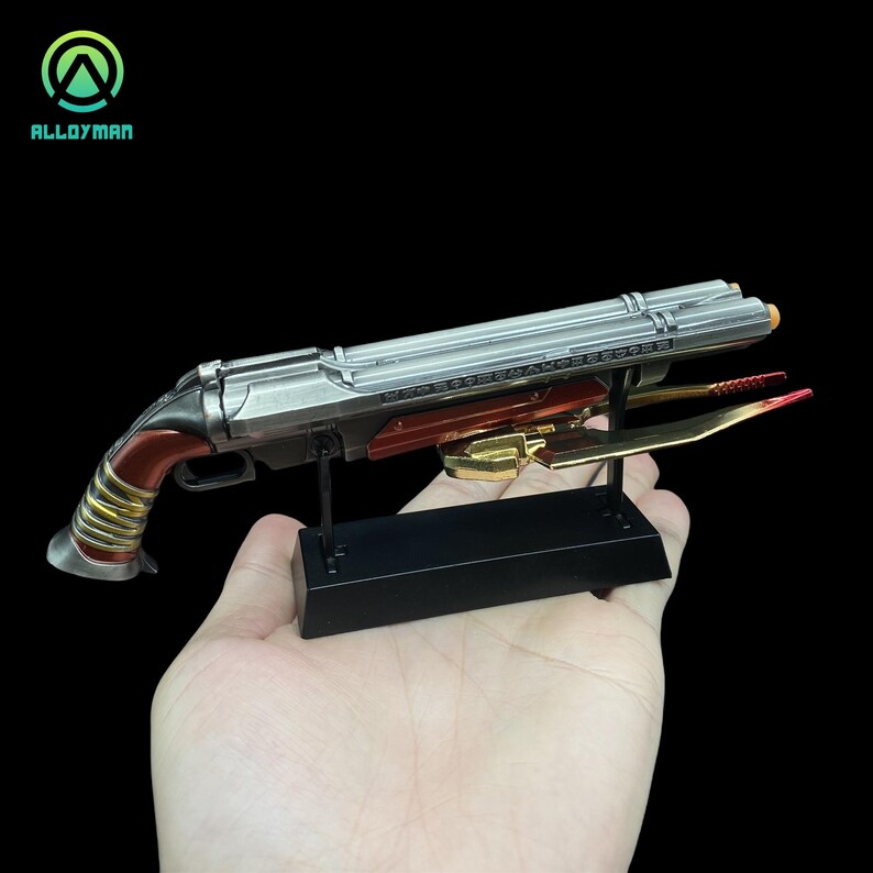 Pu&ograve; includere: Una replica in metallo argentato e rosso di un fucile a pompa futuristico con una lama dorata attaccata alla canna. L'arma &egrave; esposta su un supporto nero.