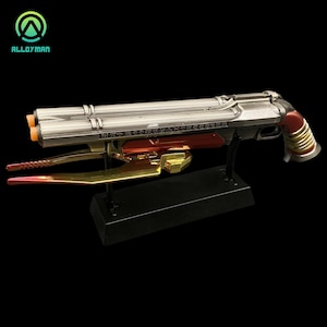 Pu&ograve; includere: Una replica in metallo argentato e rosso di un'arma immaginaria con una lama dorata attaccata alla parte inferiore. L'arma &egrave; su un supporto nero. L'arma ha il testo "N77" e "BOOMSHA-KALAKA" su di essa.
