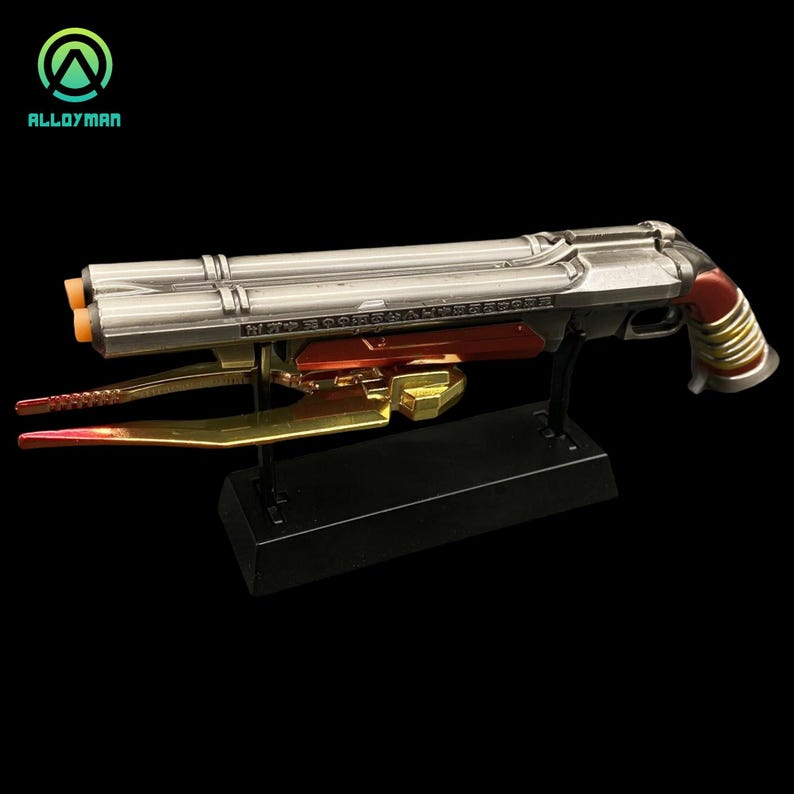 Pu&ograve; includere: Una replica in metallo argentato e rosso di un'arma immaginaria con una lama dorata attaccata alla parte inferiore. L'arma &egrave; su un supporto nero. L'arma ha il testo "N77" e "BOOMSHA-KALAKA" su di essa.