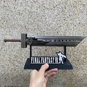 May include: A detailed replica of a large, silver sword with a brown handle and a black stand. The stand features the text "FINAL FANTASY VII" and a white silhouette. The sword is displayed against a textured background.