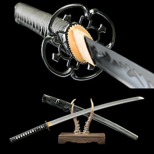 May include: A Japanese katana sword with a black handle and a silver blade. The sword is displayed with its scabbard on a wooden stand with deer antlers. The guard is a decorative, openwork design.